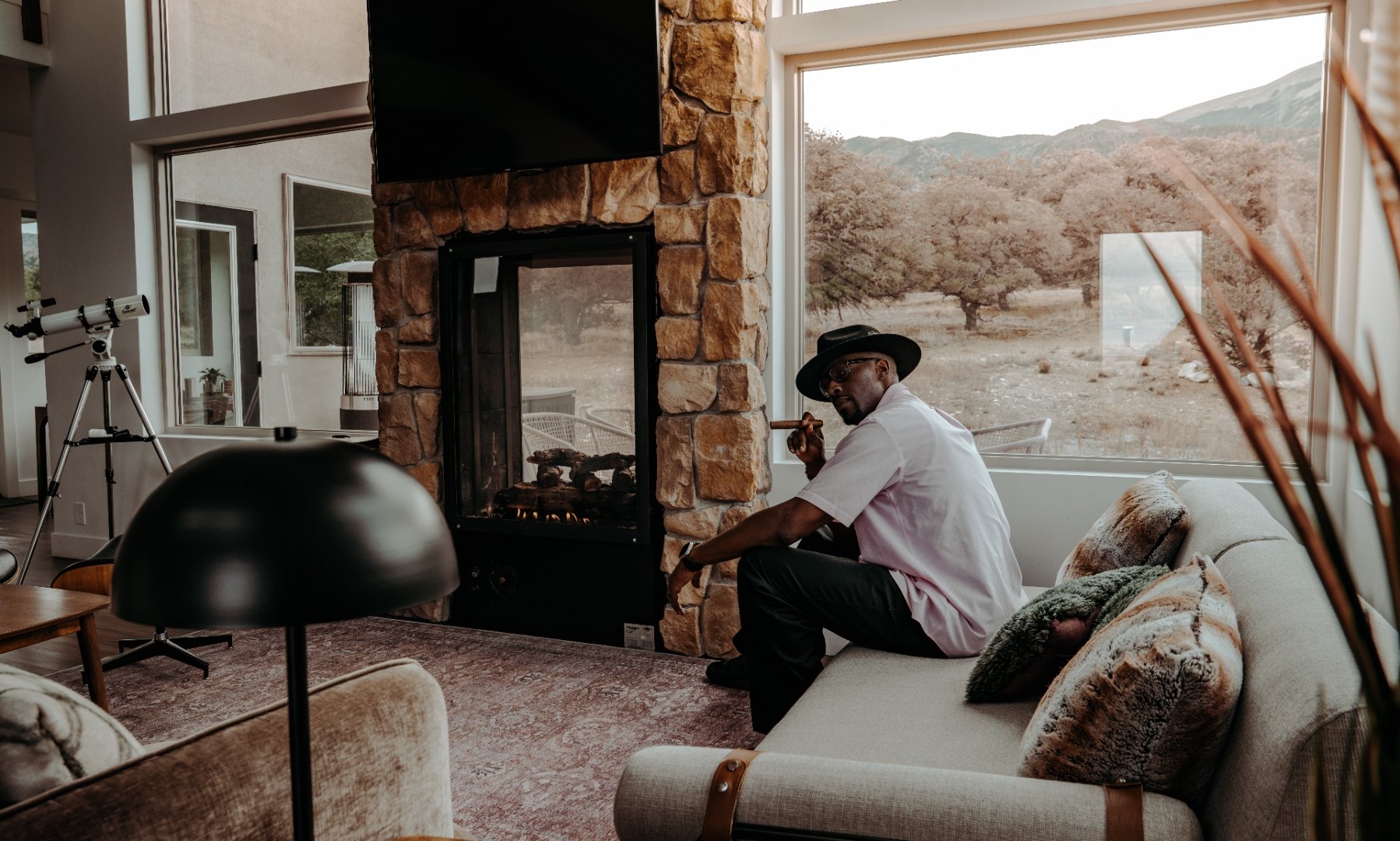 Bright desert living room with a stone fireplace and mountain view